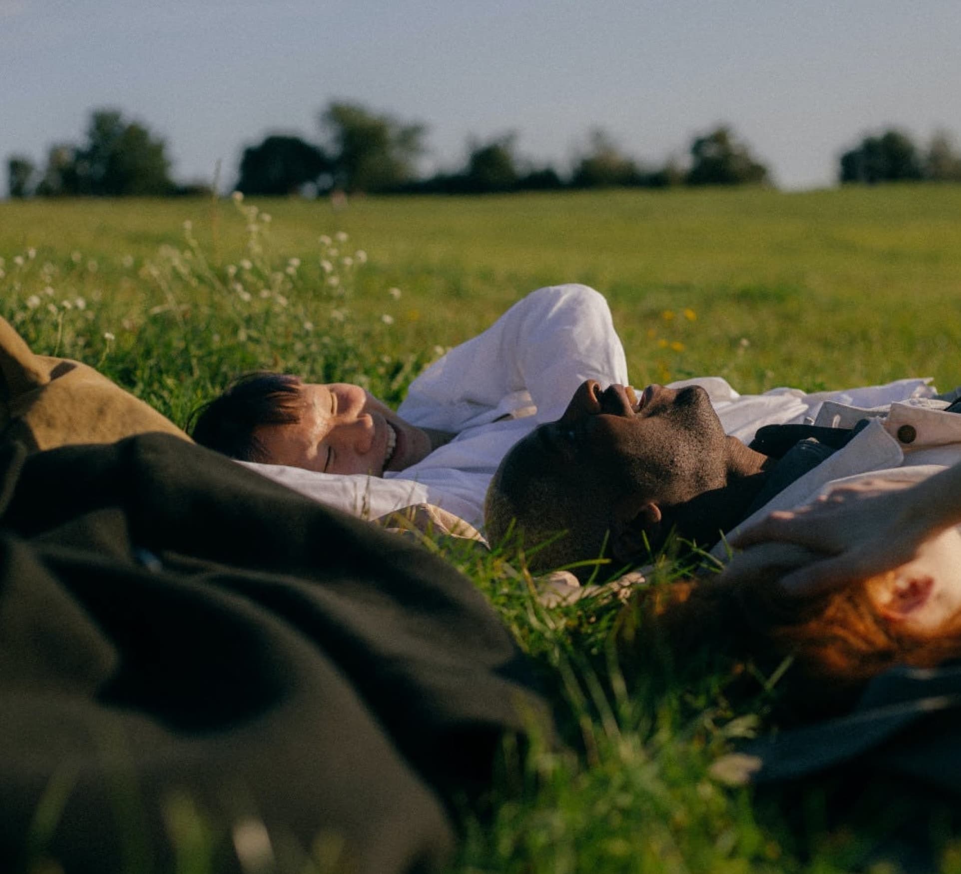 Joyroots, people laying down happily in the grass on a sunny day.